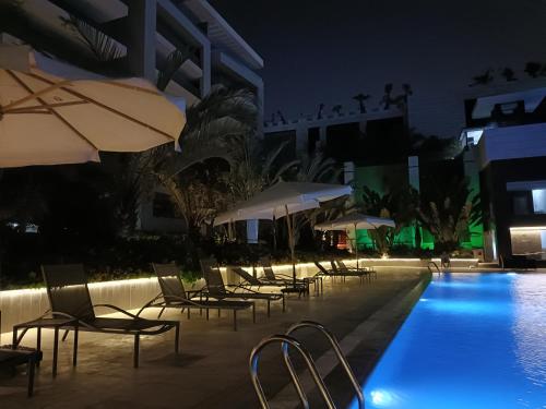开罗Sheraton Ocean 506 - Private apartments的一座带椅子和遮阳伞的游泳池位于一座建筑旁边