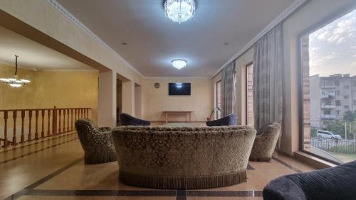 茨卡尔图博Hotel Giorgi的一间带椅子和桌子的房间以及大窗户