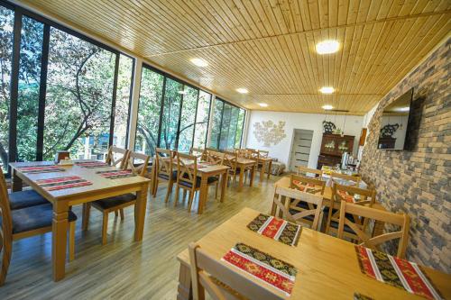 DebedMadin Eco Hotel的餐厅设有木桌、椅子和窗户。