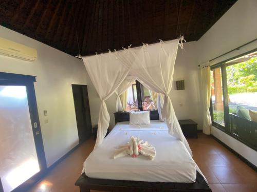 佩母德兰巴厘岛佩母得兰巴迪尼旅馆的一间卧室配有一张带毛巾的天蓬床。