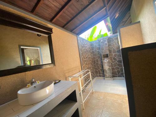 佩母德兰巴厘岛佩母得兰巴迪尼旅馆的浴室配有盥洗盆和带镜子的淋浴