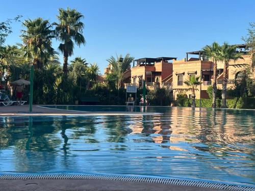 马拉喀什atlas golf resort marrakech " Maison à 03 chambres avec jardin privé "的一座棕榈树和建筑的大型游泳池