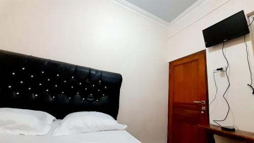 迪昂Homestay Merpati Dieng Syariah RedPartner的一间卧室配有一张带黑色床头板的床
