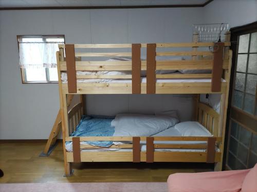 志布志市みのる民泊2号的带窗户的客房内的两张木制双层床