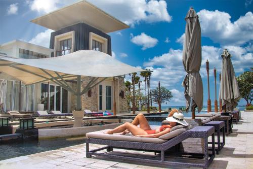 努沙杜瓦The Sakala Resort Bali All Suites的两人躺在游泳池旁的躺椅上
