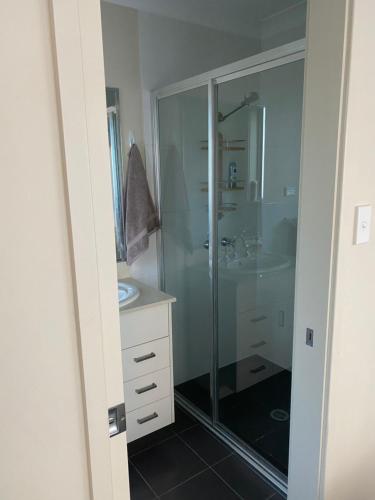 卧龙岗Private room with ensuite and parking close to Wollongong CBD的一间带玻璃淋浴和水槽的浴室