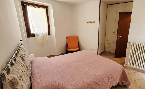 巴尔齐奥Lovely apartment in center of Barzio的一间卧室配有一张床和一张橙色椅子