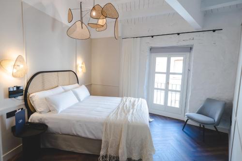 TorrojaORA Hotel Priorat, a Member of Design Hotels的卧室配有床、椅子和窗户。