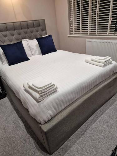 格雷夫森德Beautiful and modern House in Gravesend的一张配有白色床单和蓝色枕头的大床