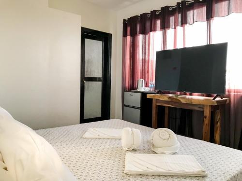 锡基霍尔E.I. SUITES的一间卧室配有带毛巾的床和平板电视