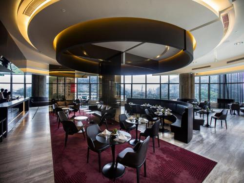深圳深圳乐酒店的一间带桌椅和大型天花板的餐厅