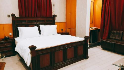 卡拉奇The Elet Business Hotel的一间卧室配有白色床单和红色窗帘