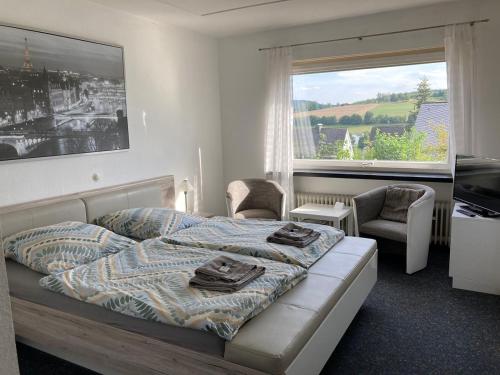 施马伦贝格Bed & Breakfast Weisser Stein的一间卧室配有一张床、两把椅子和一个窗户