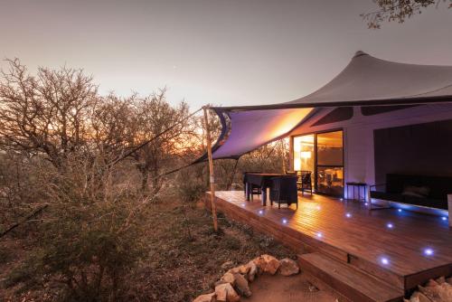 侯斯普瑞特Oase by 7 Star Lodges - Greater Kruger Private 530ha Reserve的木制甲板上的帐篷,配有桌椅