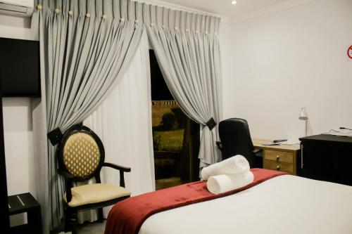LobatsePitikwe Hill Guesthouse的一间卧室配有一张床、一张书桌和一个窗户。
