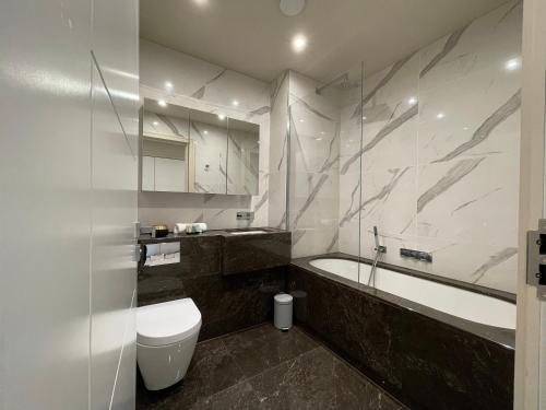 齐格威尔luxurious, 2 bed, 2 bath penthouse apartment in highly desirable Chigwell CHCL F8的带浴缸、卫生间和盥洗盆的浴室
