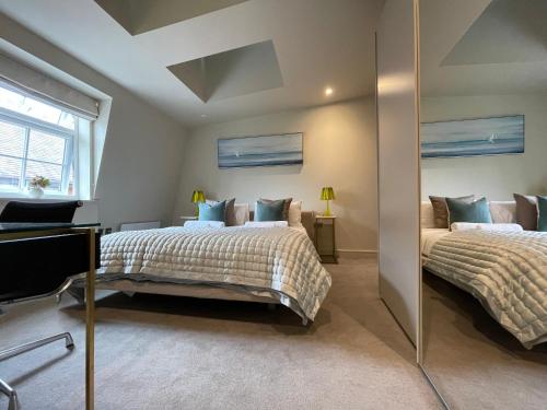 齐格威尔luxurious, 2 bed, 2 bath penthouse apartment in highly desirable Chigwell CHCL F8的一间卧室配有两张床和镜子
