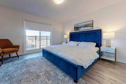 布兰普顿NEWLY BUILT LUXURIOUS 3BRM TOWN HS/AIRPORT/PARKING的卧室设有一张蓝色大床和一扇窗户。