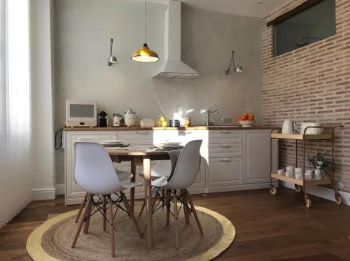 莱昂Lloēco - Art & Design Guest House的厨房配有木桌和白色椅子