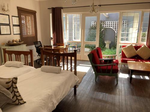 约翰内斯堡Home From Home, Waverley B&B, Johannesburg的客厅配有两张床和一张桌子及椅子