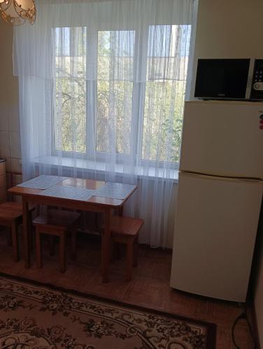 阿拉木图Квартира на Абая的厨房配有桌子、冰箱和窗户。