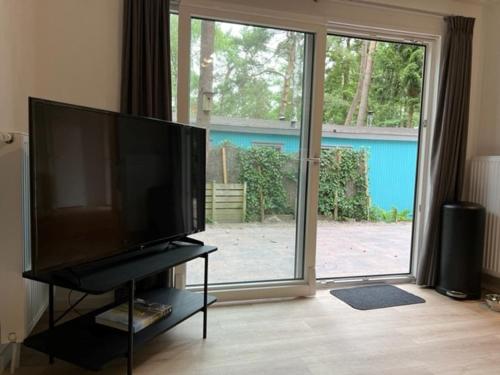 洪德洛Chalet Hoenderloo的客厅设有大电视和大型滑动玻璃门