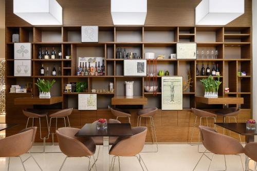 莱切Eos Hotel的餐厅设有桌椅和装有葡萄酒的架子