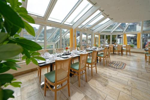 玛丽亚阿尔姆Hotel Edelweiss的温室里带桌椅的用餐室