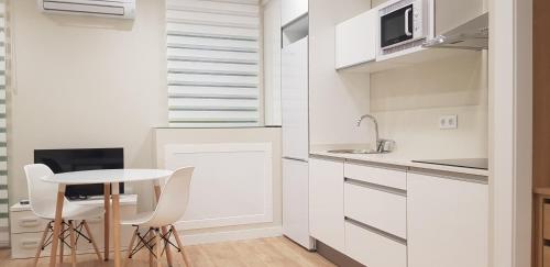 阿尔巴塞特Apartamentos Ilustración的白色的厨房配有小桌子和椅子