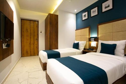 孟买HOTEL ASTROS的两张位于酒店客房的床,拥有蓝色的墙壁