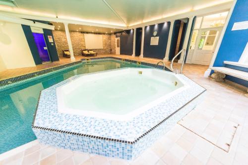 格兰奇奥沃桑茨农庄酒店的一座位于中间的大型游泳池,游泳池设有浴缸