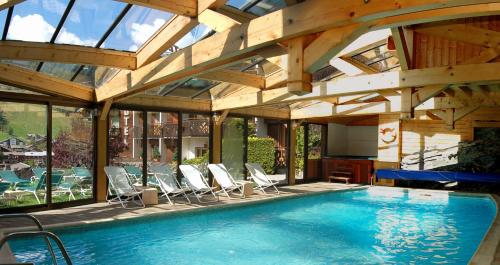 莫尔济讷Hôtel Les Côtes, Résidence Loisirs et Chalets的一个带椅子和木制天花板的室内游泳池
