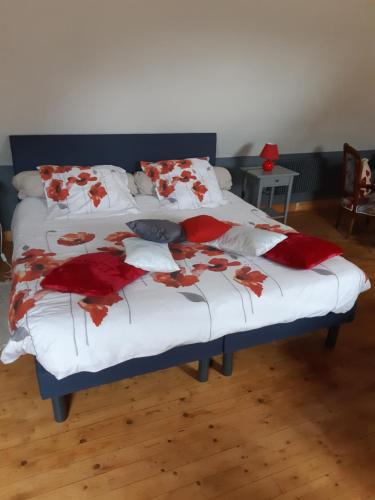 Saint-UrbainLes Coquelicots的一张带红白毯子和枕头的床