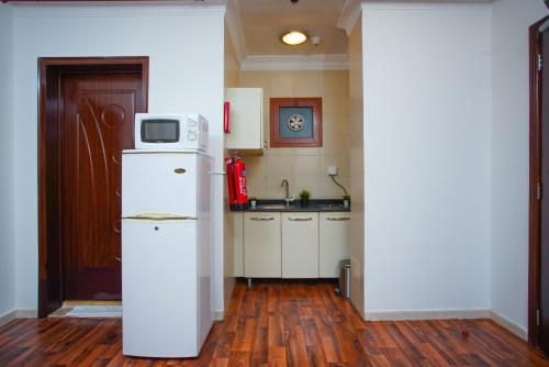 多哈别墅套房酒店的厨房配有冰箱,上面配有微波炉