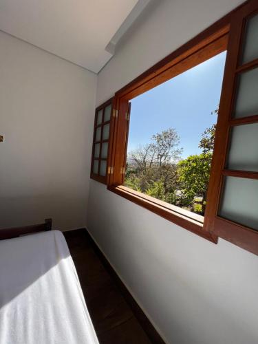 圣湖镇Casa da Vista - LAGOA SANTA的卧室设有窗户,享有树木美景