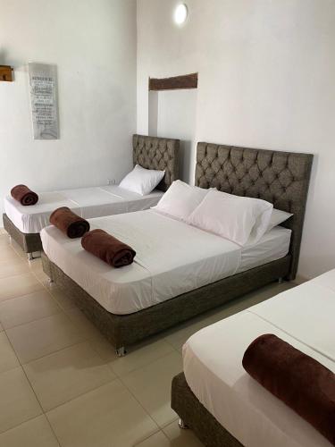 蒙波斯HOTEL PLAZA BOLIVAR MOMPOX ubicado en el centro histórico con parqueadero interno的卧室设有2张床和白色的墙壁。