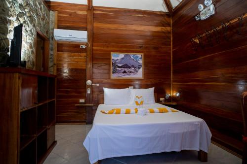 邦劳Alona Austria Resort的卧室配有一张白色大床和木墙