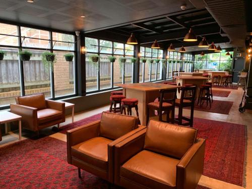 悉尼Southend Hotel的餐厅设有皮椅、桌子和窗户。
