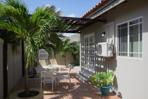 努尔德Beach Homes Aruba的房屋旁的天井配有椅子和棕榈树