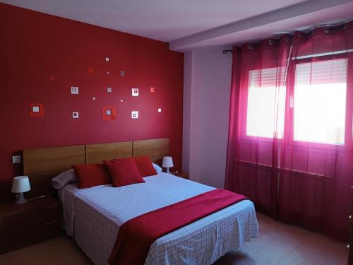 曼萨纳雷斯Manzanares的一间卧室设有红色的墙壁和一张带红色枕头的床