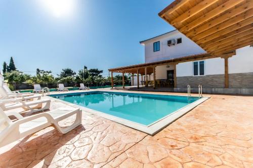 拉纳卡Reel Paradise Villa, Cyprus的一个带椅子的游泳池以及一座房子