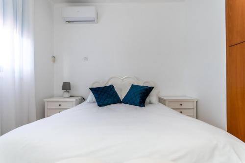 拉纳卡Reel Paradise Villa, Cyprus的一张带两个蓝色枕头的白色床