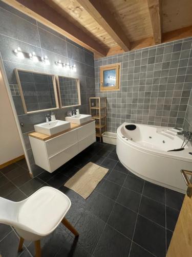 莱德萨阿尔卑斯Chalet le Lotus Blanc的带浴缸、两个盥洗盆和浴缸的浴室。