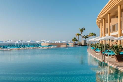 莫罗德哈布雷Iberostar Selection Fuerteventura Palace的度假村的游泳池,配有椅子和遮阳伞
