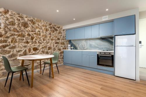干尼亚TheJoy Residence Apartments的厨房配有蓝色橱柜和桌椅