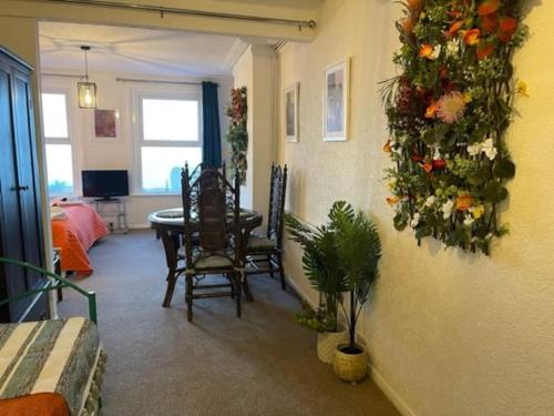 伊斯特布恩"The Caribbean" Seafront Apartment的客厅设有餐桌,墙上挂着鲜花