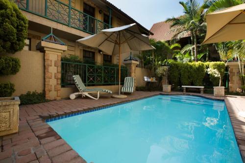 比勒陀利亚柯尔特古典套房酒店的一个带两把椅子和遮阳伞的游泳池