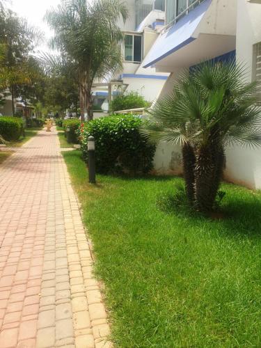 穆罕默迪耶Résidence SUN SET BEACH à 200 m de mer的棕榈树建筑旁的砖砌人行道