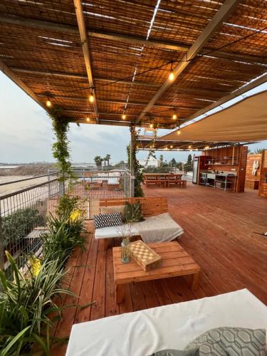 AtlitAtlit Rooftop Glamping的平台上设有长椅和桌子的庭院