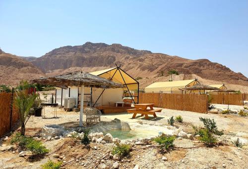 Metsoke DragotTRANQUILO - Dead Sea Glamping的沙漠中带桌子和野餐桌的庭院